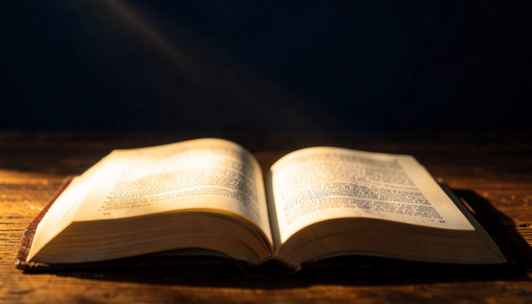 Warm golden light falling across an open Bible on a wooden surface, with deep navy shadows in the background, conveying reverence and generosity.