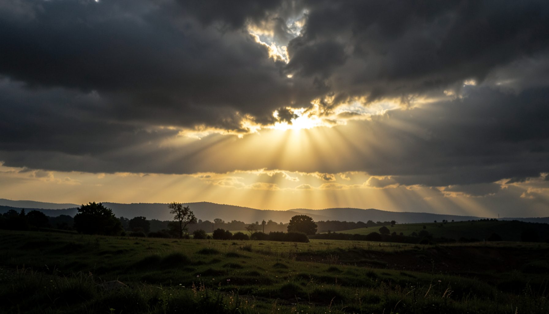 Soft golden light breaking through dark clouds over a quiet landscape, conveying watchfulness and hope